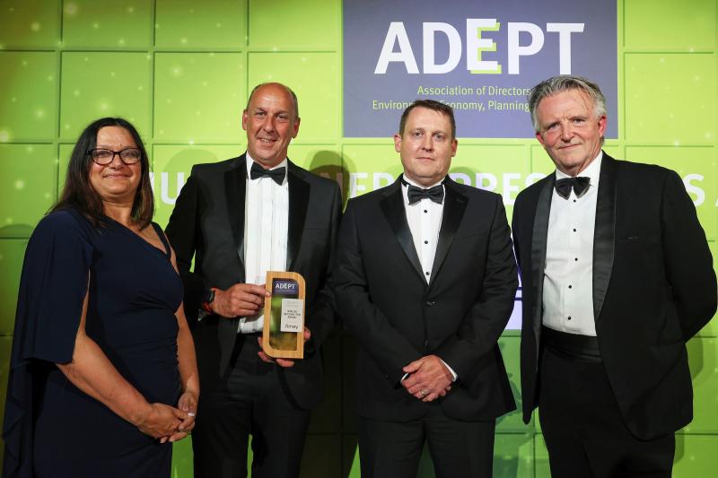 Picture shows 4 people (1 woman, 3 men) standing against a green backdrop with the ADEPT logo. One of the men is being presented with an award.