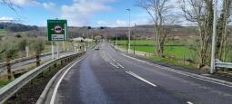 UK highway with green fields, trees and signage pointing to Kilmarnock, Law and Brownlee